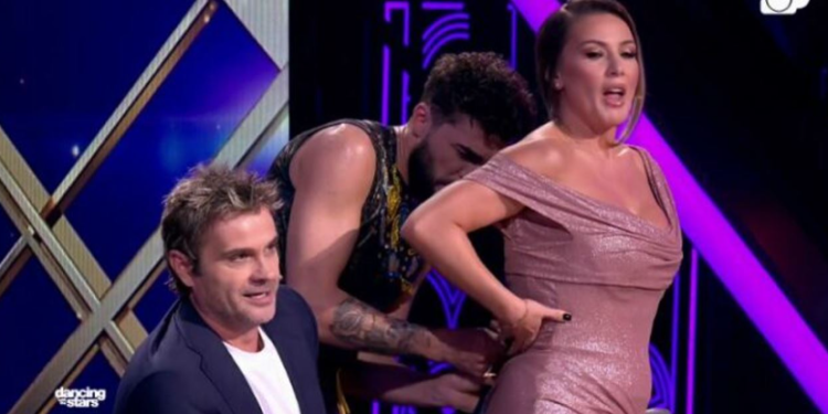 Olta Gixharit i ndodh e papritura, i zbërthehet fustani në skenë. Iliri refuzon ta ndihmojë, vjen Sardi